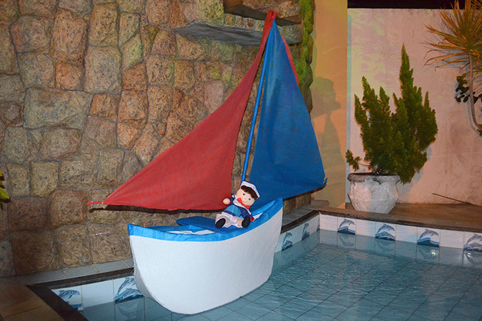 Barco feito de isopor e velas de tecido exposto na piscina